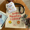 Bolso de tela Aluna estampado con frase Solo buenas vibras sobre mesa con una bolsita para la lavadora Aluna